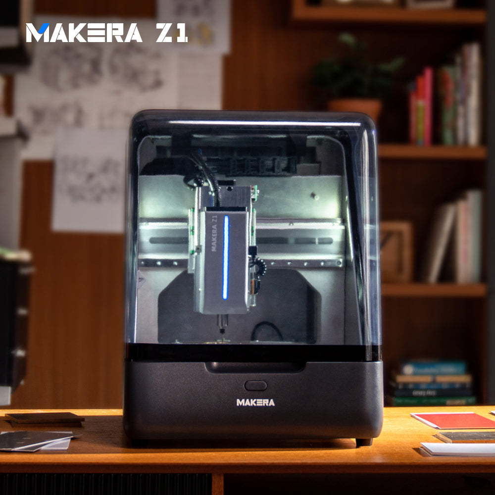 Makera Z1 hobby CNC machine on a wooden desk in a home studio, with its enclosed work area illuminated.